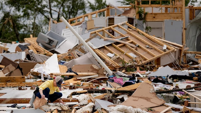 Valerie Bernhardt looks through debris at her stormed damaged home...