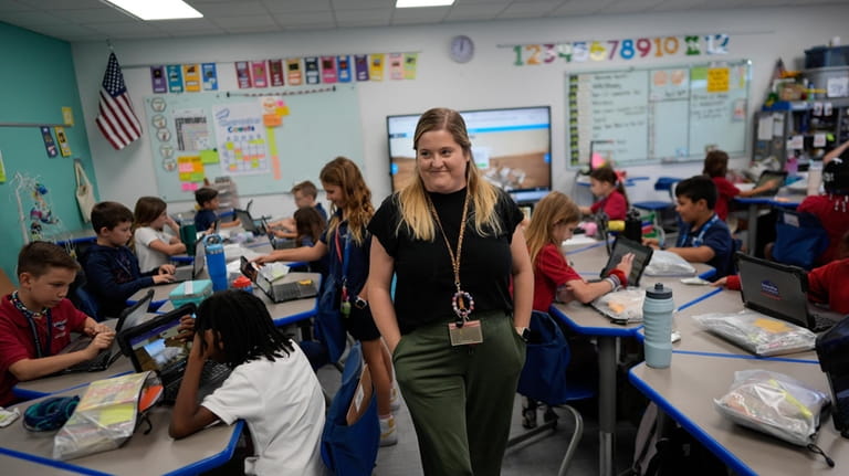 Third grade teacher Megan Foster walks through her classroom as...