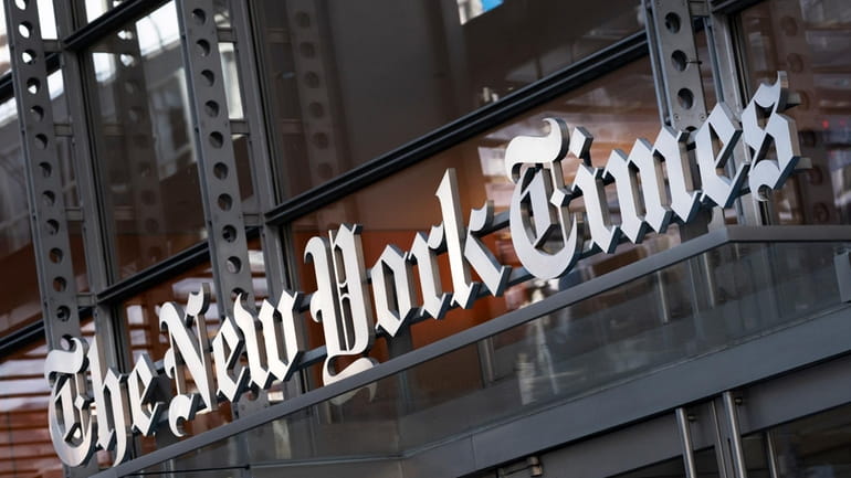 A sign for The New York Times hangs above the...