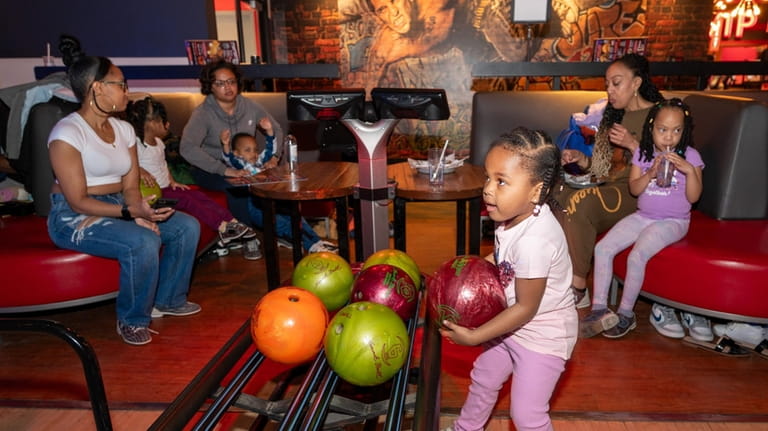 Claire Burton, 3, of West Hempstead, chooses a bowling ball...