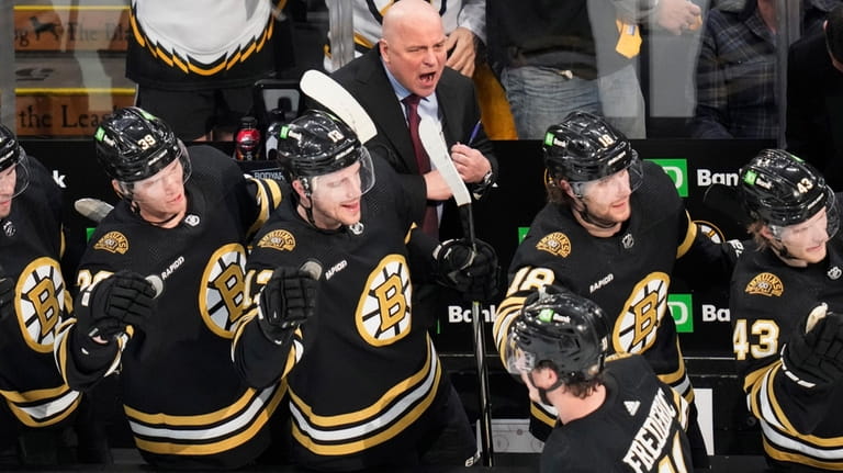 Boston Bruins head coach Jim Montgomery cheers after a goal...