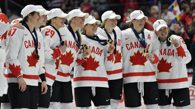 Team Canada players pose with their medals after beating the...