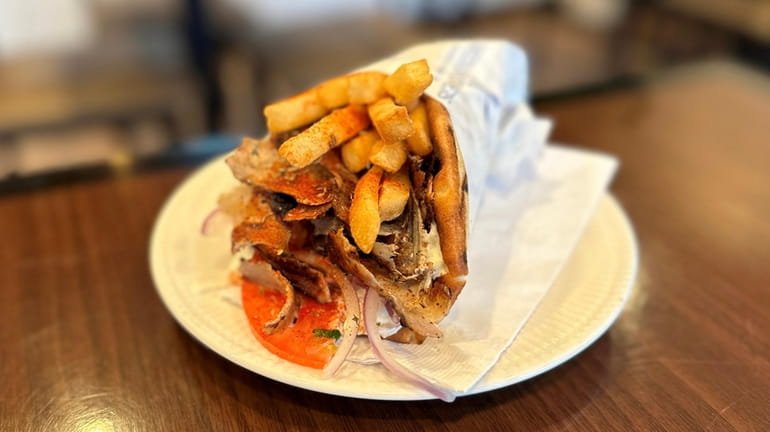 An authentic Greek gyro, with pork and French fries, is...