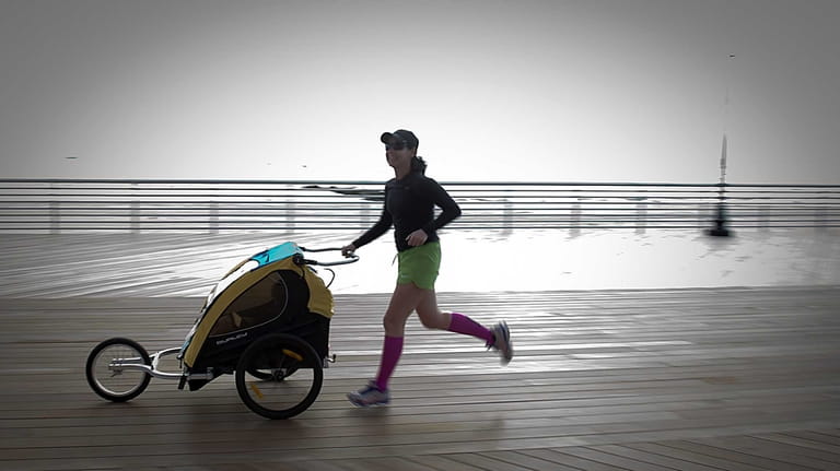 A woman running while pushing a baby stroller on the...