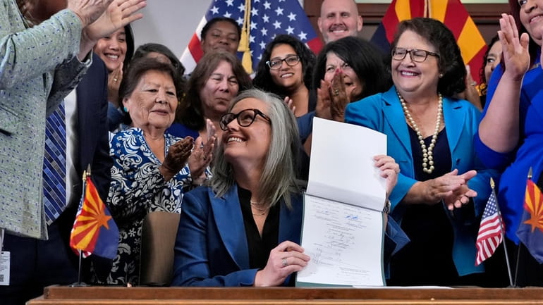 Arizona Gov. Katie Hobbs smiles after signing the repeal of...