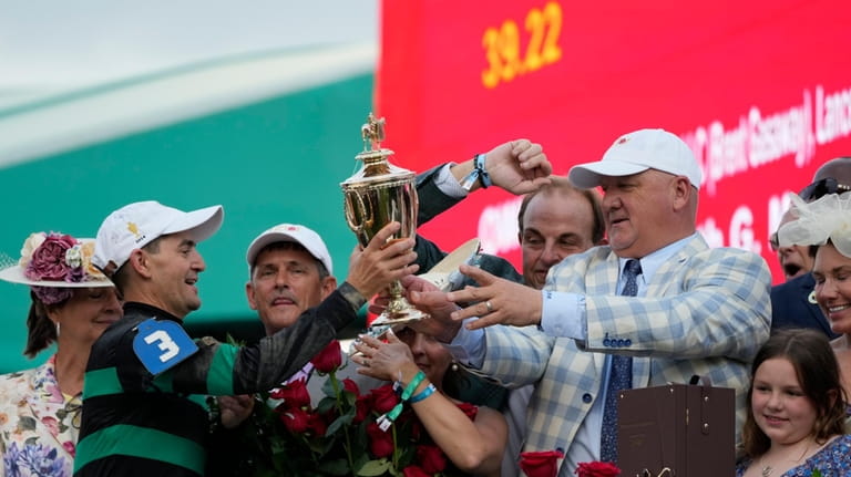Trainer Kenneth McPeek, right, hand off the trophy to jockey...