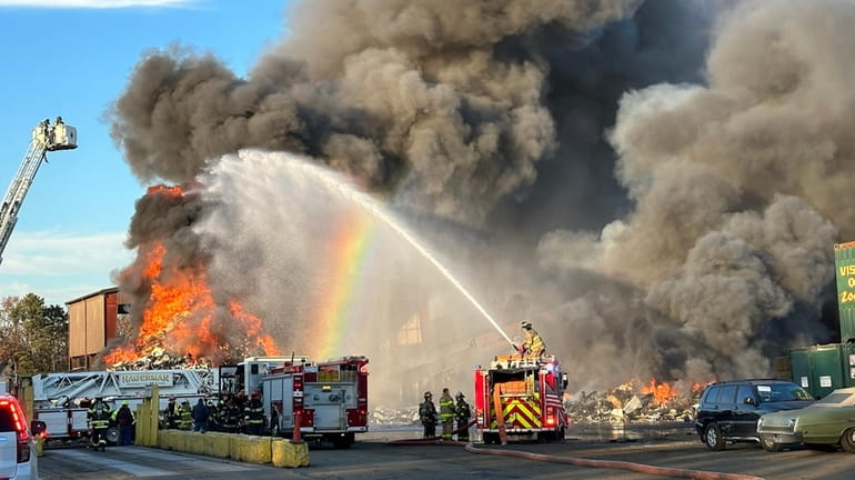 Firefighters work to put out the fire at the recycling...