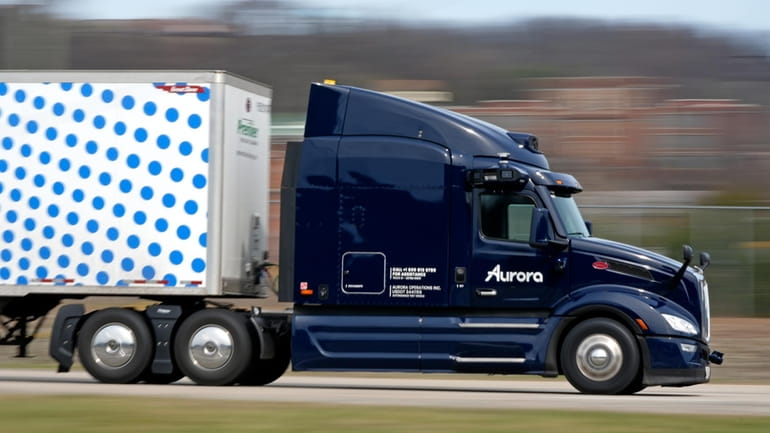 A self-driving tractor trailer maneuvers around a test track in...