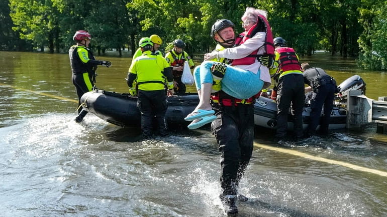 A Conroe, Texas, firefighter carries a woman evacuated in a boat...