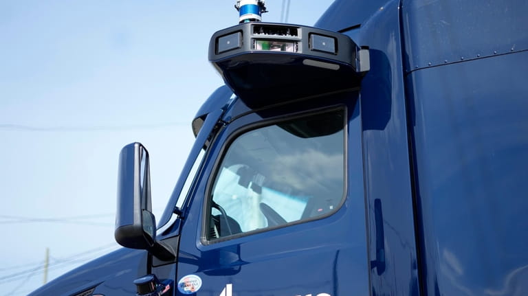 A self-driving tractor trailer is displayed at a test track...