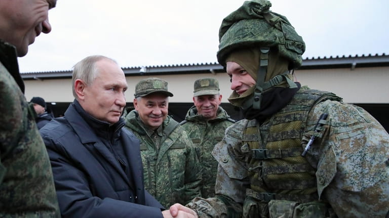 Russian President Vladimir Putin shakes hands with a soldier and...