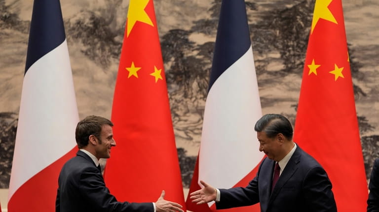 FILE- French President Emmanuel Macron, left, shakes hands with Chinese...