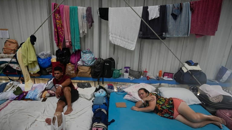 People who evacuated their flooded homes rest in a shelter...