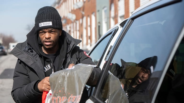 Antonio Moore, 24, of Baltimore, hands out designer t-shirts reading...