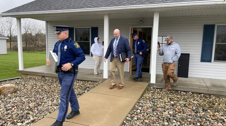 The Michigan State Police exit the Adams Township Hall after...