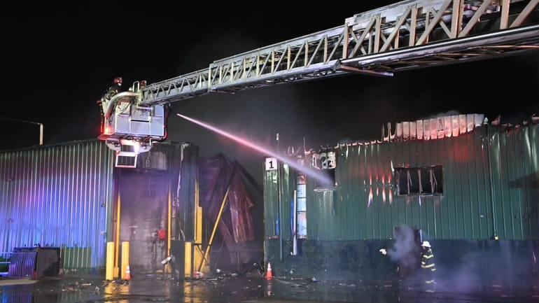 Firefighters extinguish a fire at the Long Island Waste Service...