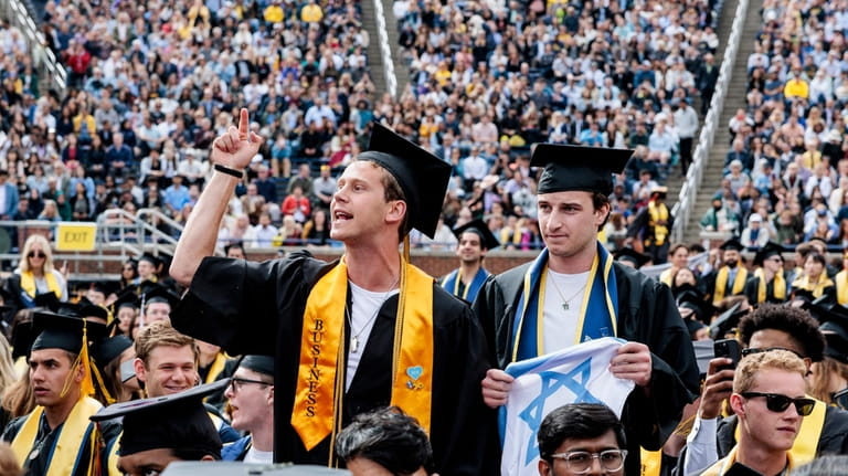 Graduates sporting Israeli flags and pins shout at Pro-Palestinian protesters...