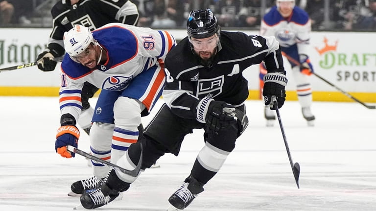 Los Angeles Kings defenseman Drew Doughty, right, takes the puck...