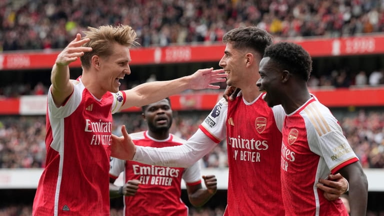 Arsenal's Bukayo Saka, right, celebrates with teammates after scoring his...