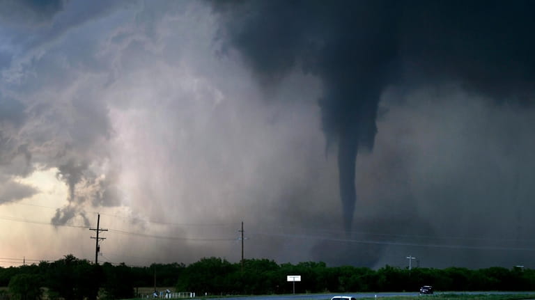 A tornado spins west of Hawley, Texas as cars pass...