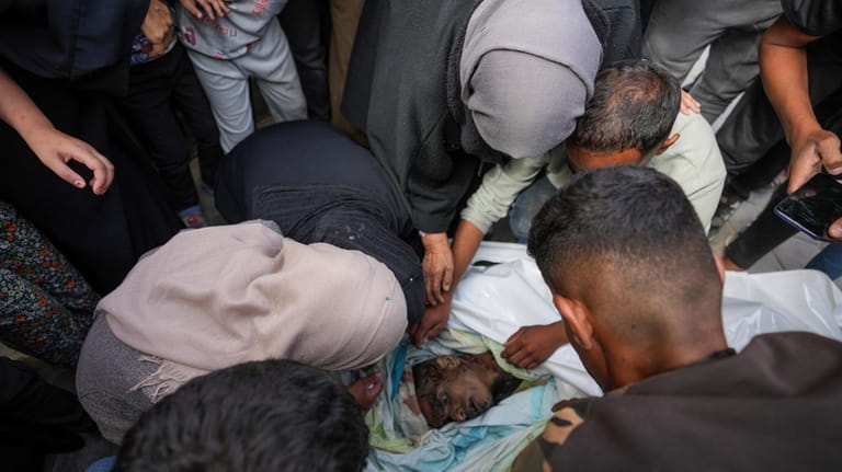 Mourners look at the bodies of Palestinians who were killed...