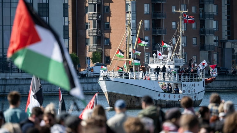Demonstrators carrying Palestinian flags look on as the Ship to...