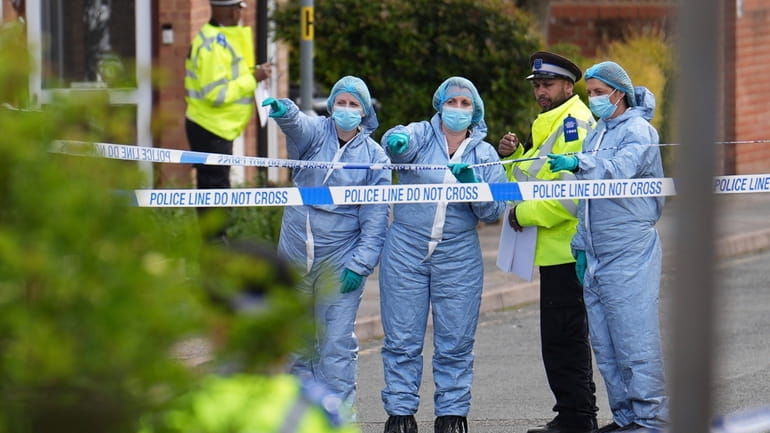 Forensics officers gesture near the scene of an attack in...