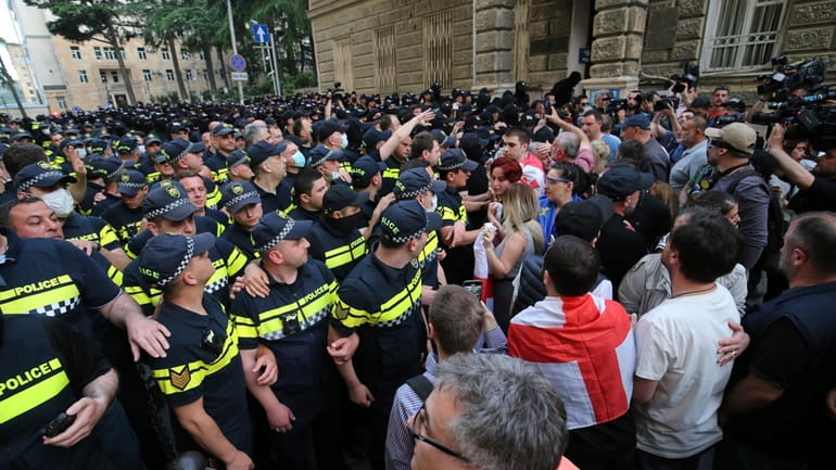 Police face demonstrators during an opposition protest against "the Russian...
