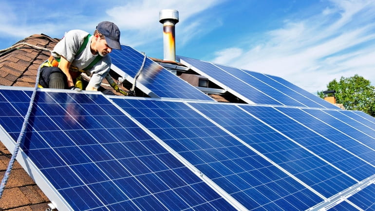 Man installing alternative energy photovoltaic solar panels on roof