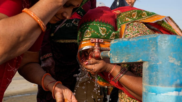 Women drink water from a public tap near the River...
