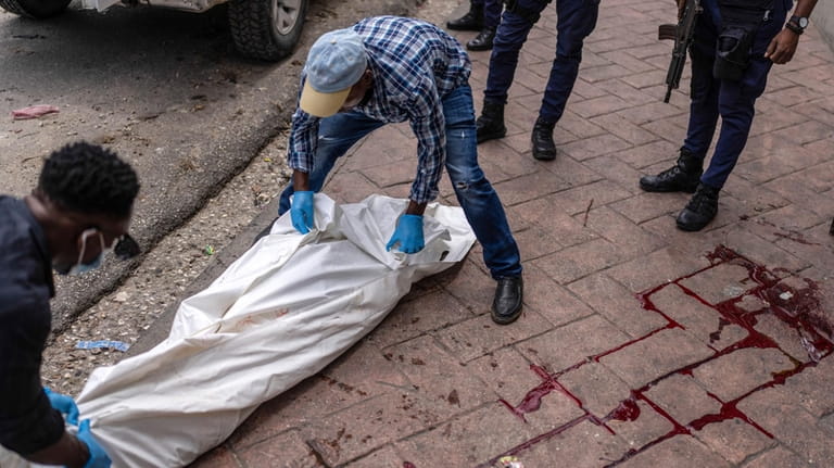 Forensic workers remove the body of a man shot dead...