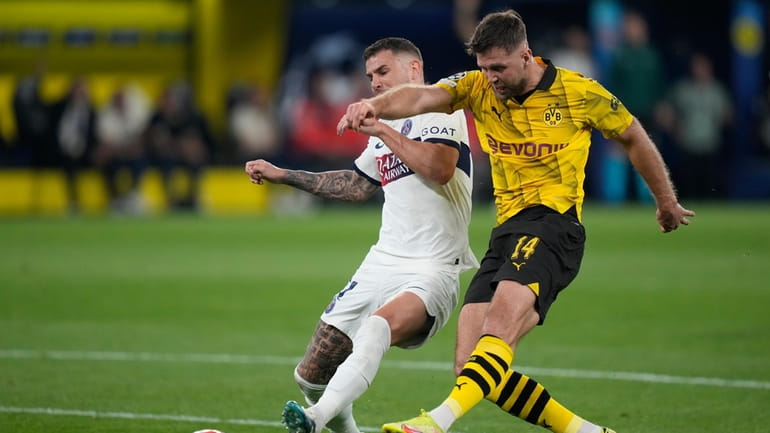 Dortmund's Niclas Fuellkrug, right, is challenged by PSG's Lucas Hernandez...
