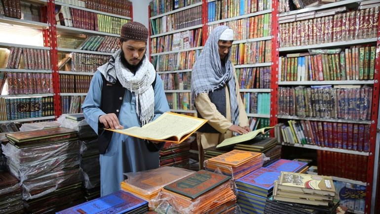 Afghans read books in a specialized religious bookstore in Kabul,...