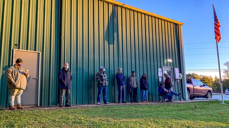 Voters wait for the polls to open to cast their...