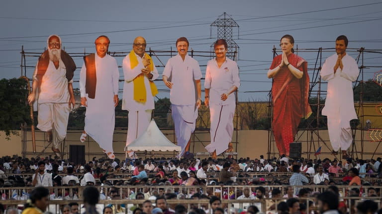 Giant cutouts of opposition political party leaders tower over supporters...