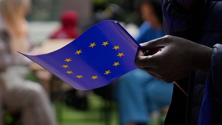 FILE- A man holds a European Union flag as he...