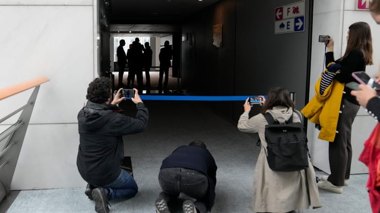 People take images as security officers gather in a corridor...
