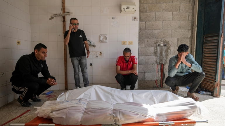 Palestinians react next to the bodies of their relatives who...