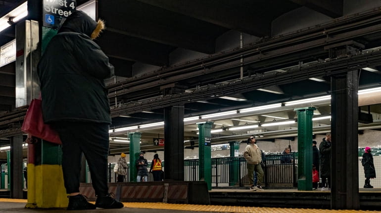 Passengers wait on a subway train platform at the West...