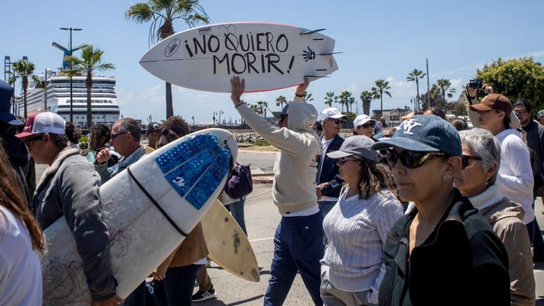 A demonstrator holding a bodyboard written in Spanish " I...