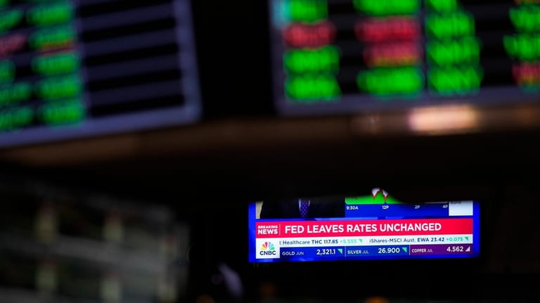 A screen displays news about the interest rate as traders...