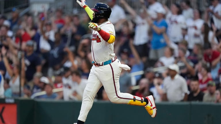 Atlanta Braves designated hitter Marcell Ozuna gestures as he runs...