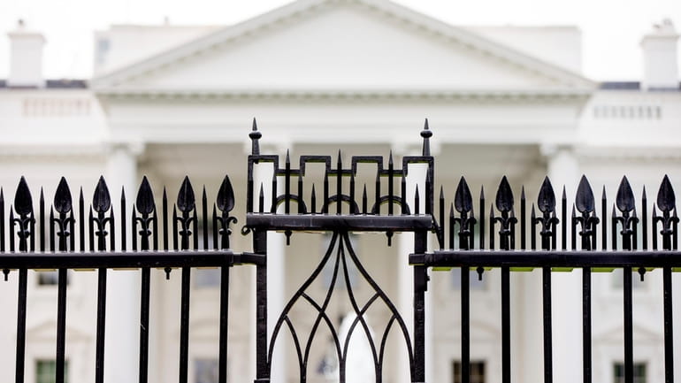 The White House is visible through the fence at the...