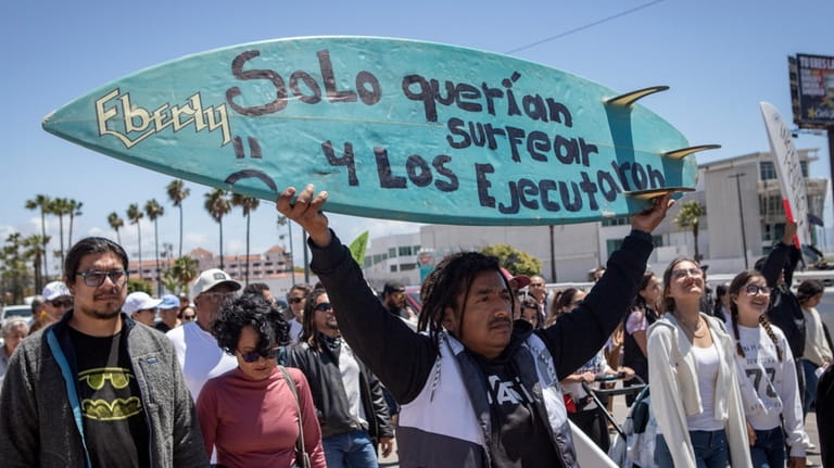 A demonstrator holding a bodyboard written in Spanish " They...