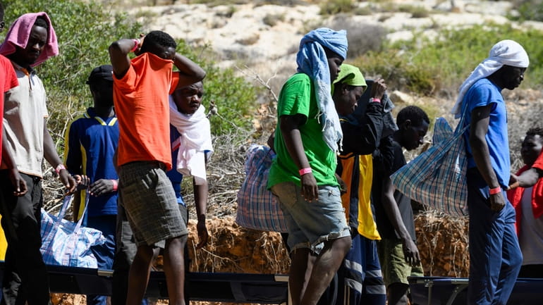 Migrants walk in Lampedusa Island, Italy, Friday, Sept. 15, 2023....