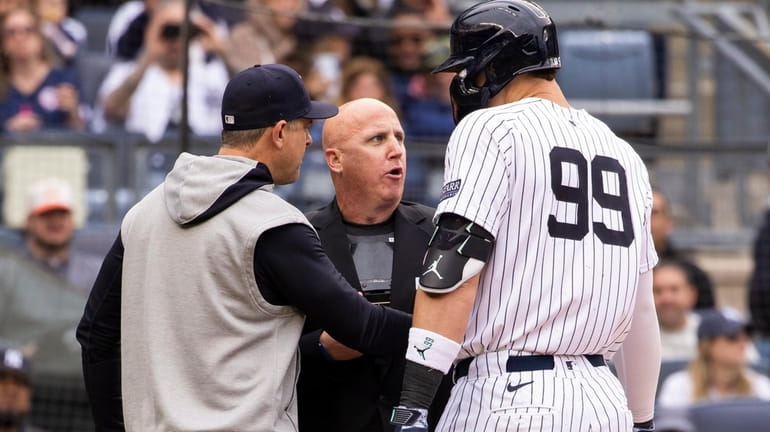 Yankees manager Aaron Boone, left, argues with home plate umpire...