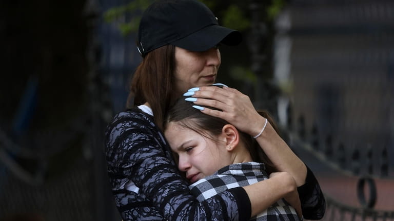 A woman hugs a girl near the Vladislav Ribnikar school...