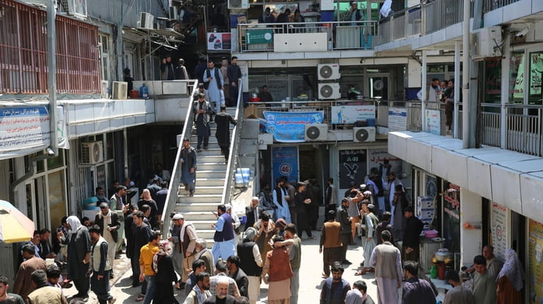 Afghans walk around a downtown currency exchange market in Kabul,...