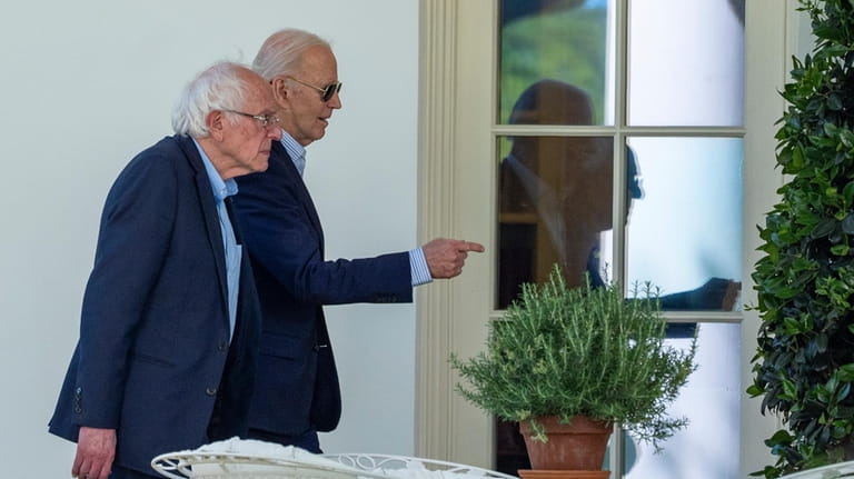 Sen. Bernie Sanders, I-Vt., left, walks with President Joe Biden...