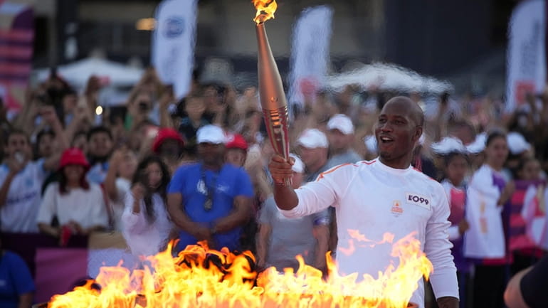 Torchbearer Didier Drogba of France holds the torch to light...